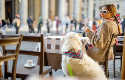 Dog and woman sitting outside a cafe in Italy.