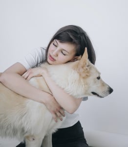 woman hugging tan dog