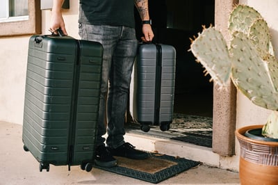 man holding luggage walking out the door
