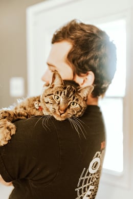 man holding tabby cat
