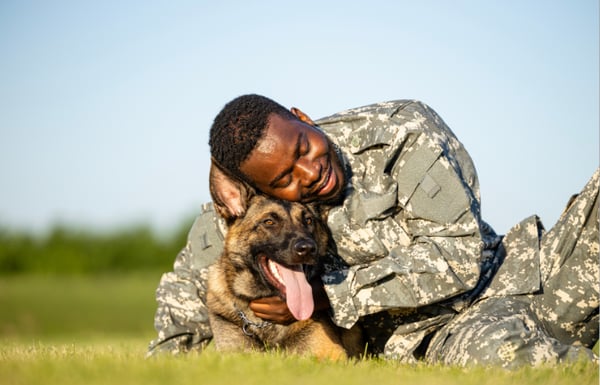 Man in army fatigues snuggled up with his dog after PCSing.