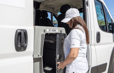 Starwood driver loading dog into an approved travel kennel.