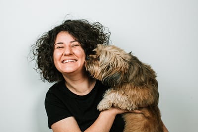 woman hugging small dog and smiling